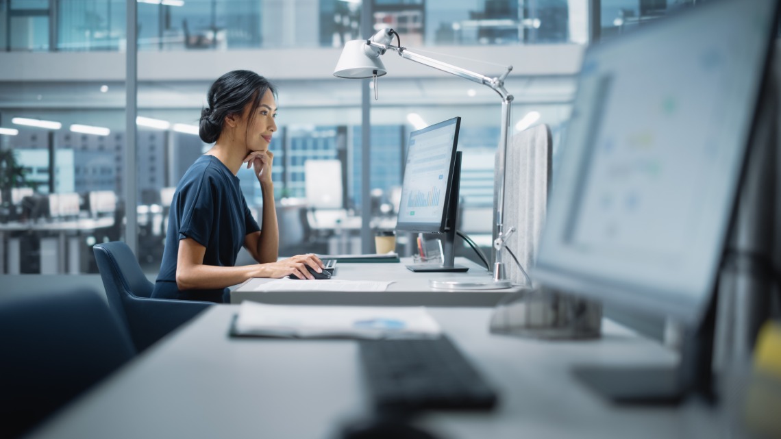 In Big Diverse Corporate Office: Portrait of Beautiful Asian Manager Using Desktop Computer, Businesswoman Managing Company Operations, Analysing Statistics, Commerce Data, Marketing Plans.